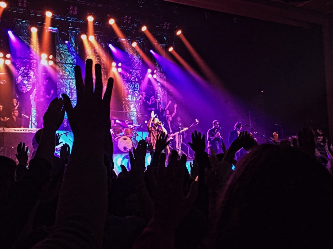 Festival crowd with hands raised under stage lights
